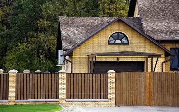 Timber boundary fence with brick pillars in front of a New Zealand home