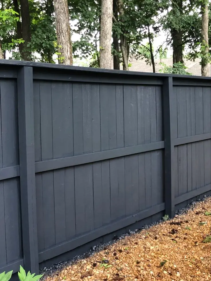 Timber fence painted black bordering a landscaped garden