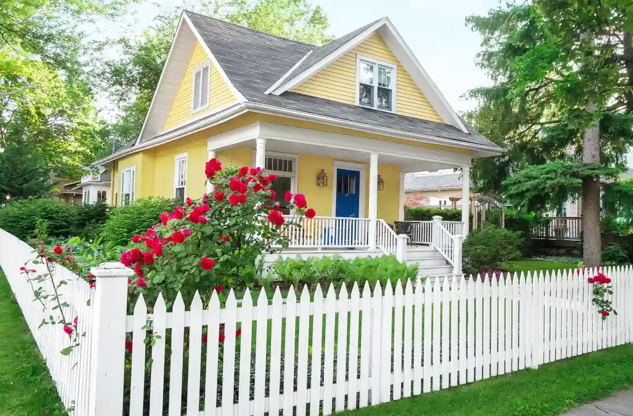 White picket fence in front of a cottage with roses