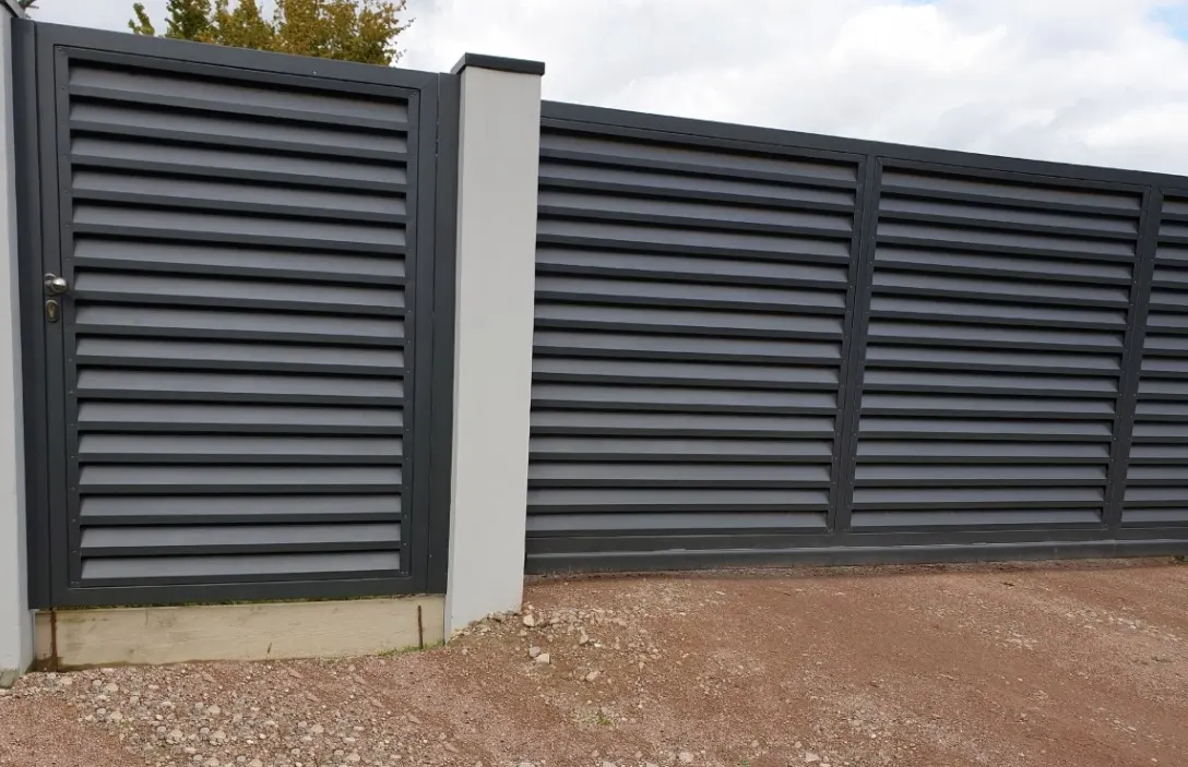 Charcoal aluminium louvre fence and matching gate alongside a driveway