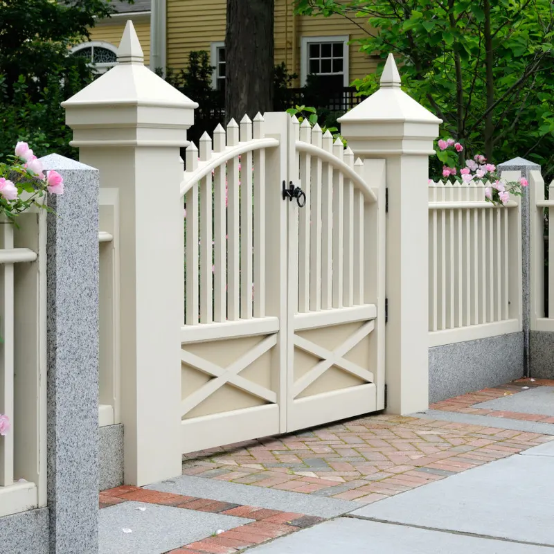 A cream wooden gate with decorative posts and cross-bracing, set in a garden setting