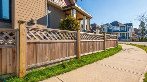Wooden garden fence with lattice panels running along a footpath beside a house