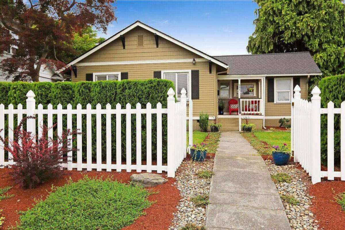 A house with a white picket fence and a walkway leading to the front door