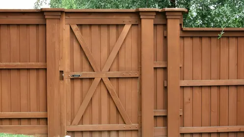 A wooden gate installed in a fence on a sloped property