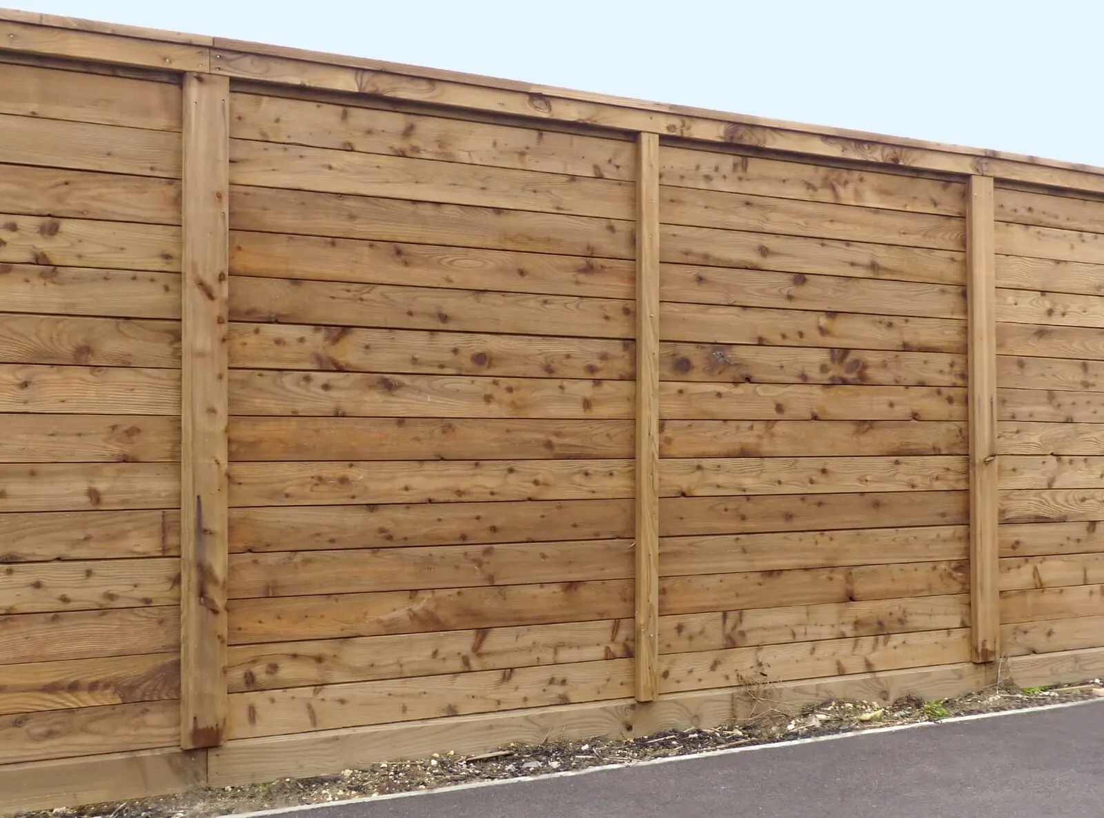 A wooden fence with vertical posts and horizontal planks
