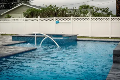 A white PVC fence surrounding a swimming pool in a backyard