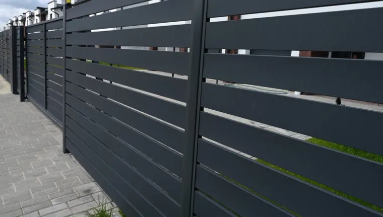 Dark grey horizontal slat fence acting as a windbreak along a property boundary